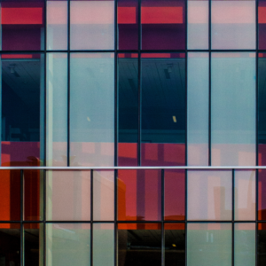 Foto da fachada de um prédio com janelas de vidros coloridos vermelhos e amarelos, com linhas verticais e horizontais pretas, que remetem ao estilo artístico de Mondrian.